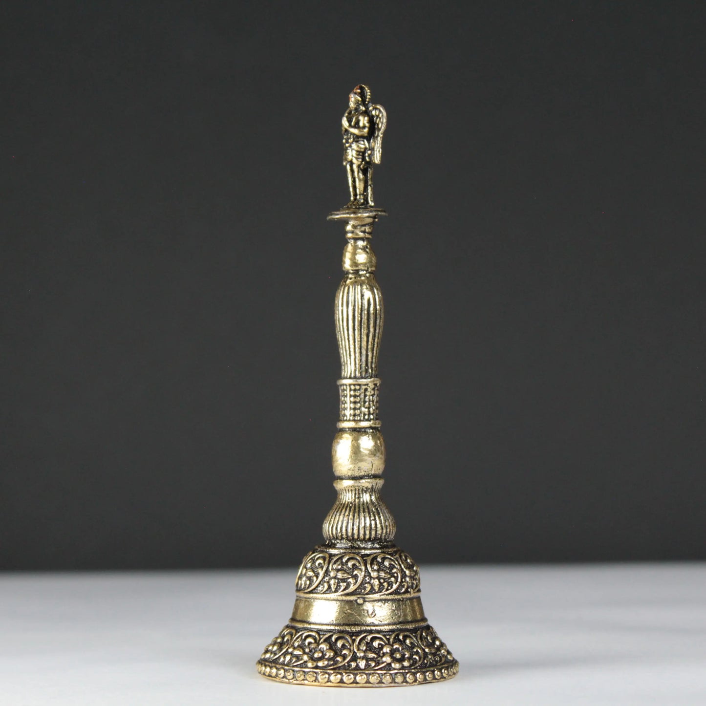 Decorative brass bell with intricate designs on a black background