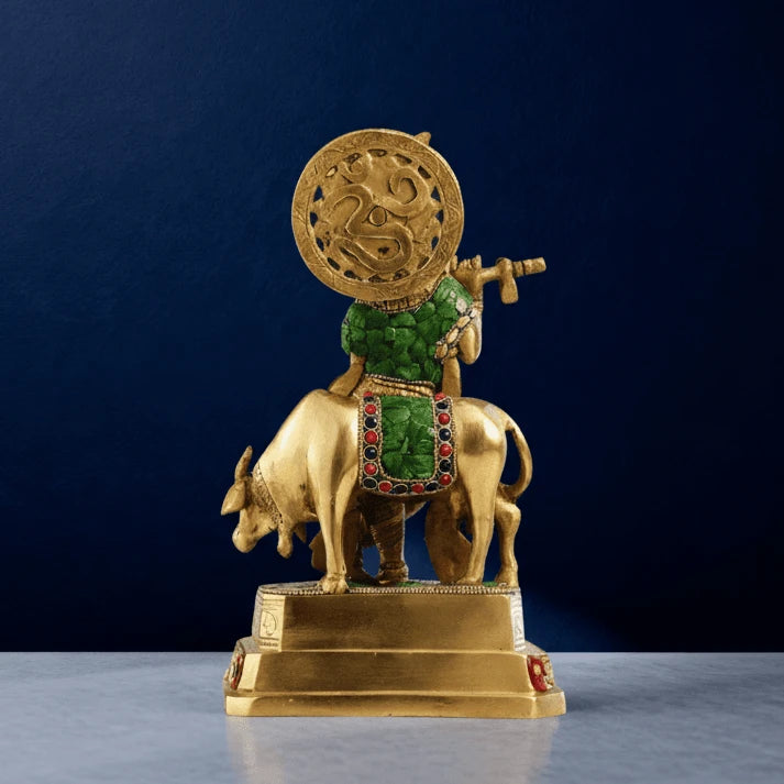 Rear view of brass Krishna with cow statue showing green stonework, engraved halo and detailed craftsmanship on solid brass base
