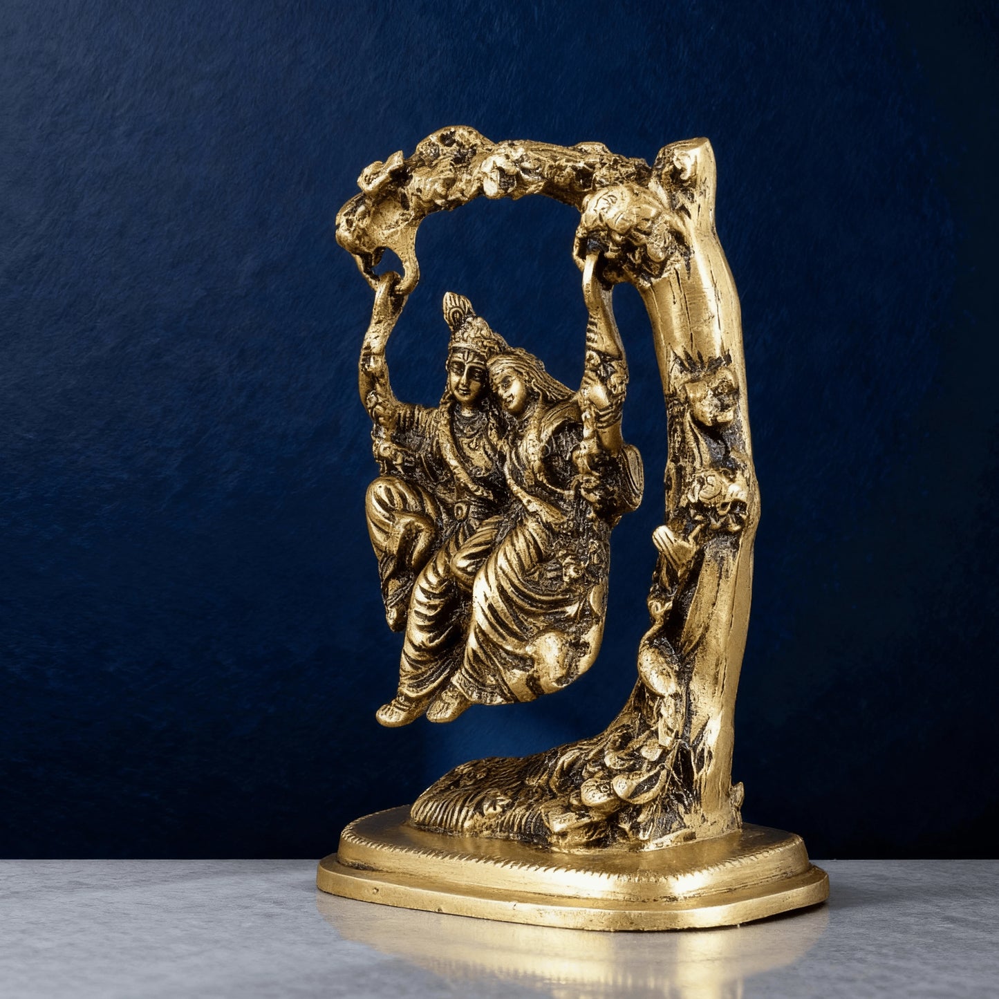 Artistic brass Radha Krishna on swing with tree arch, intricately carved premium idol for pooja room or gifting.