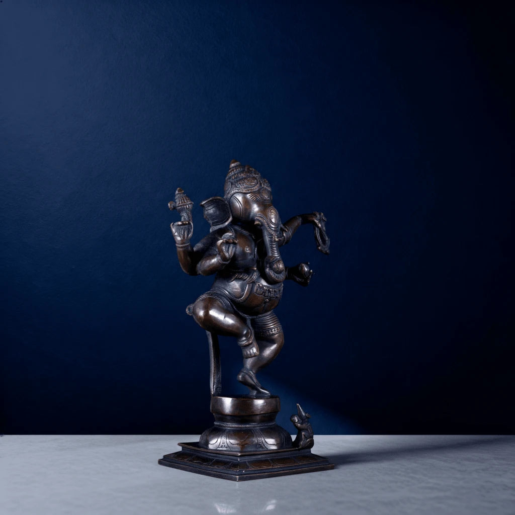 Angled shot of traditional dancing Lord Ganesha sculpture with intricate carvings and rat at base