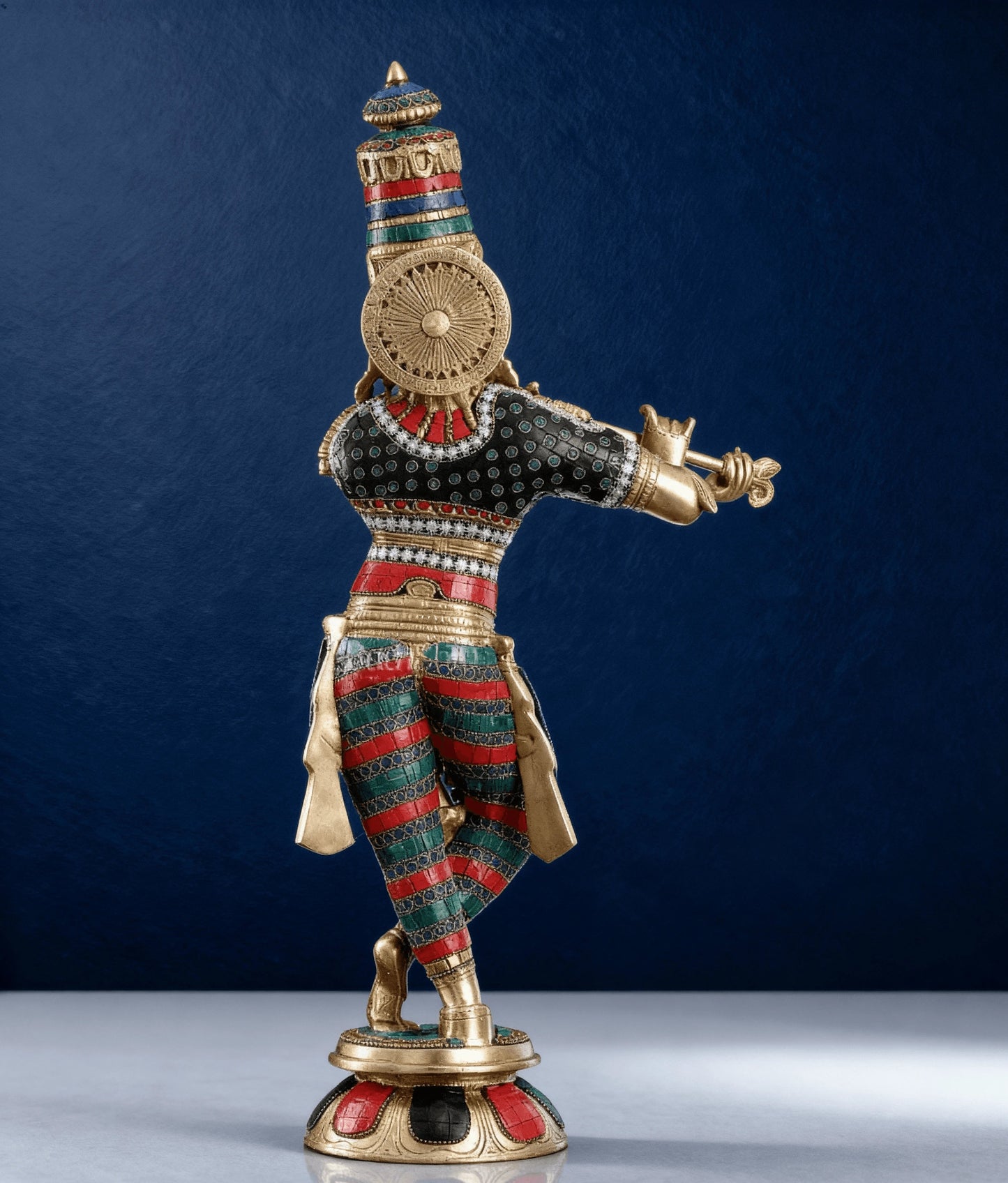 Brass hand-painted Krishna statue rear view on marble surface