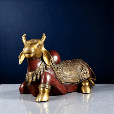 Brass Nandi statue with red body and gold detailing on a marble tabletop