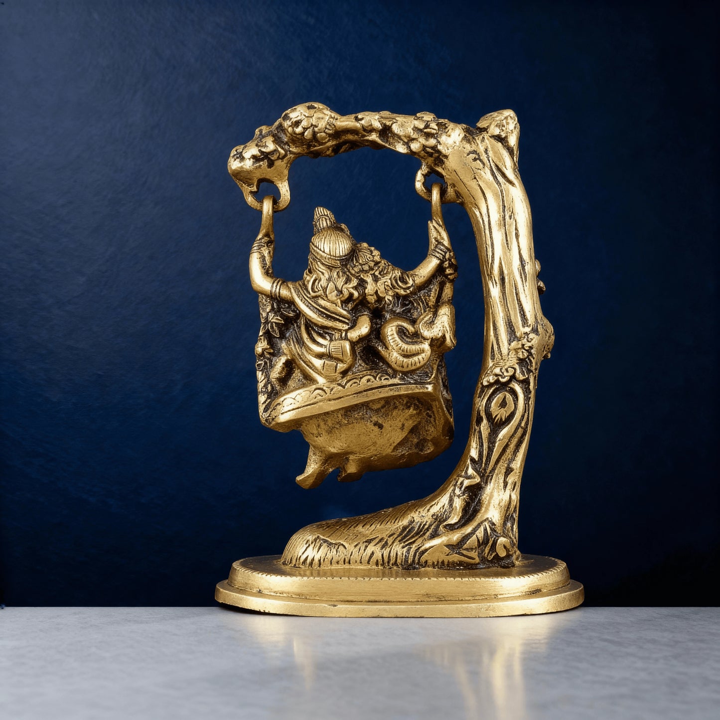 Back view of brass Radha Krishna swing statue showing detailed tree carving and artisan craftsmanship for home decoration.