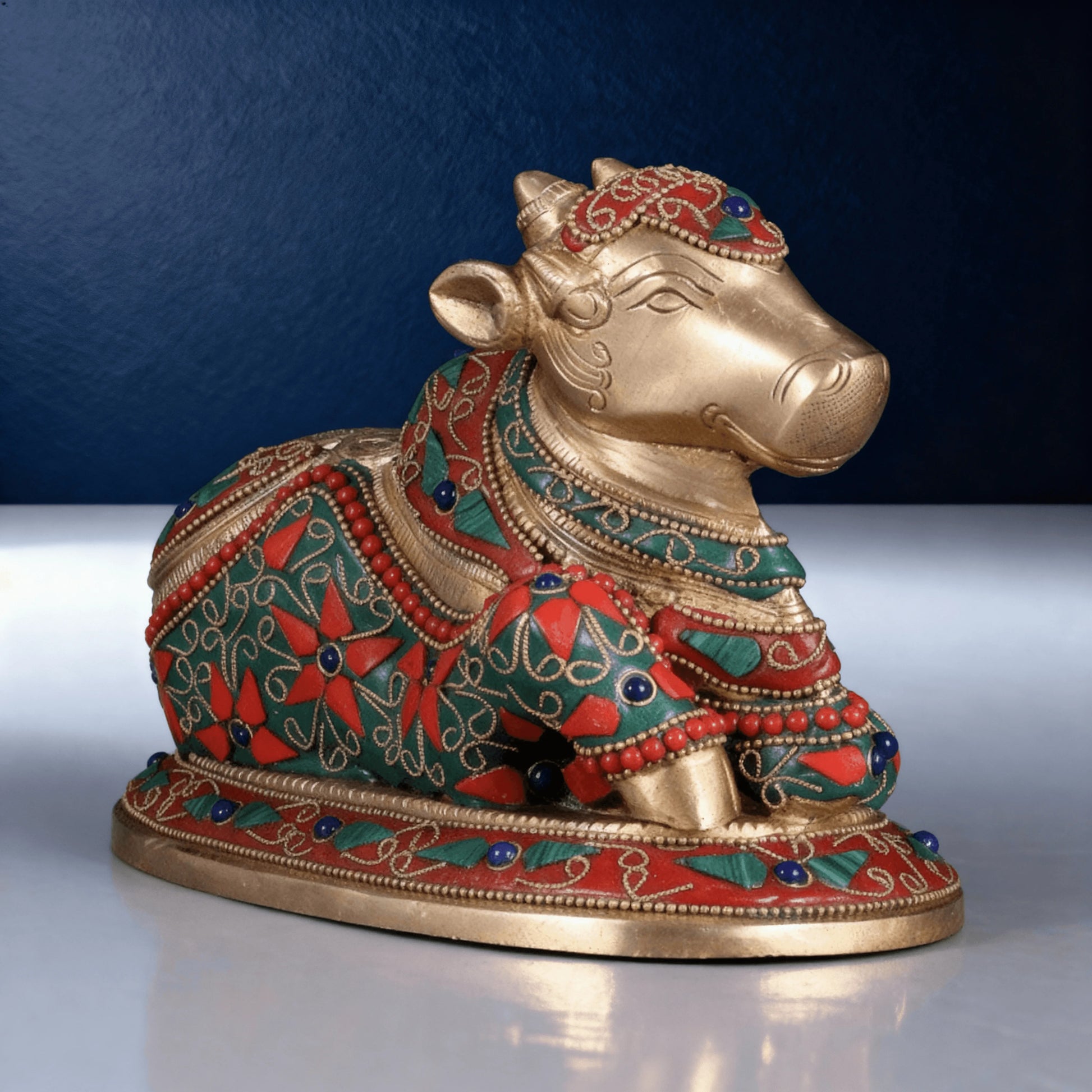 close up view of brass meenakari nandi idol showing intricate red and green artwork