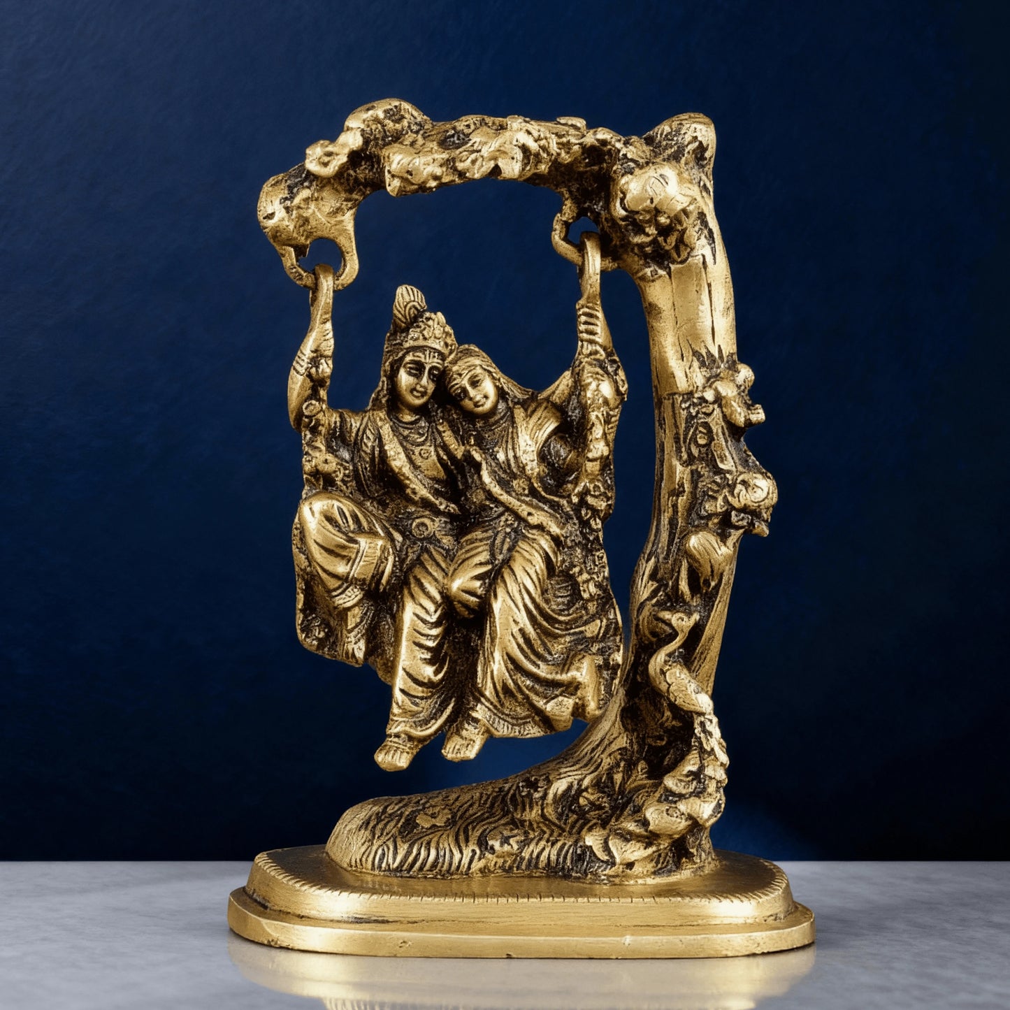 Handcrafted brass Radha Krishna jhula statue with ornate tree arch and detailed carving, perfect for spiritual home decor.