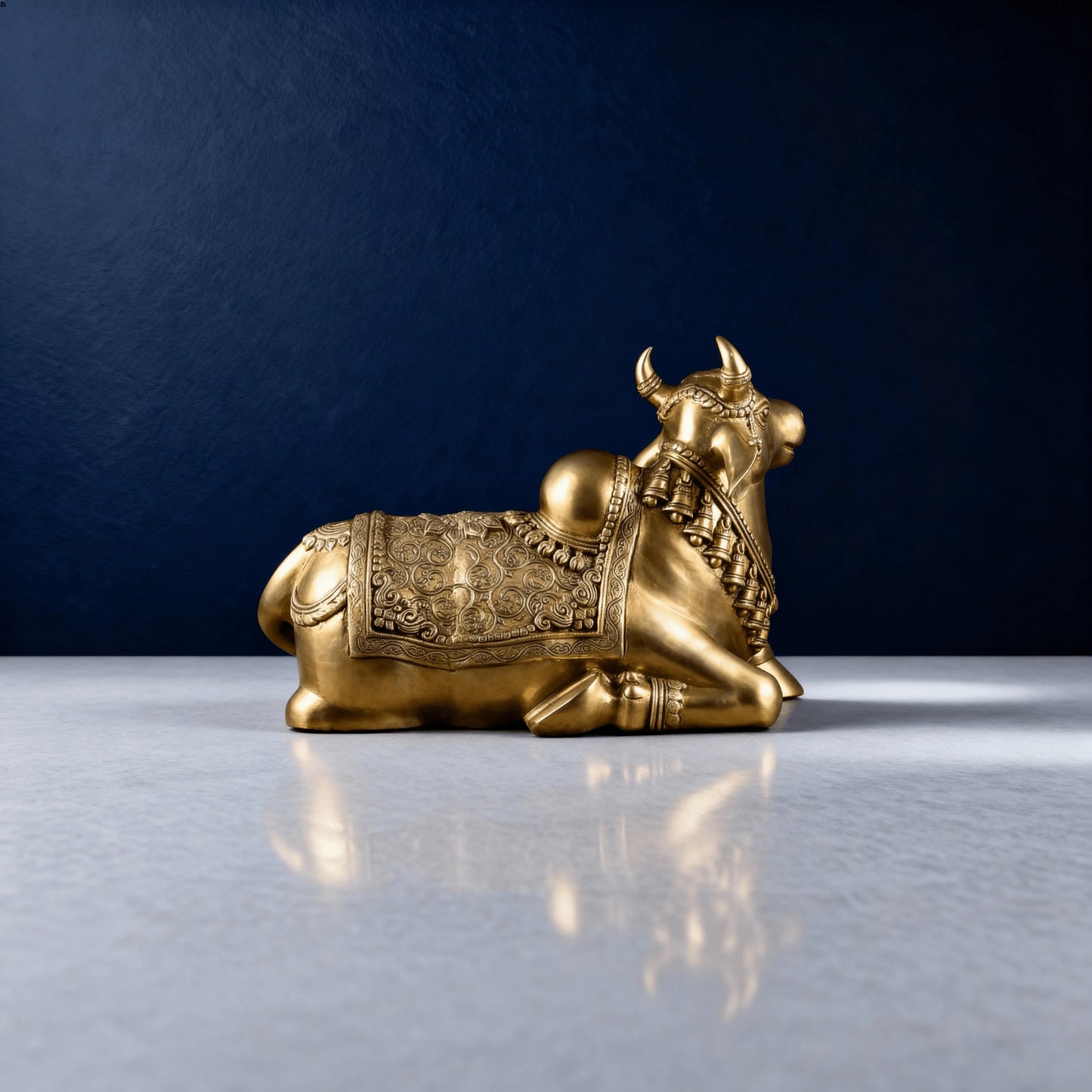 side profile of brass Nandi idol showing ornate saddle carving and smooth polished finish on a marble-like surface