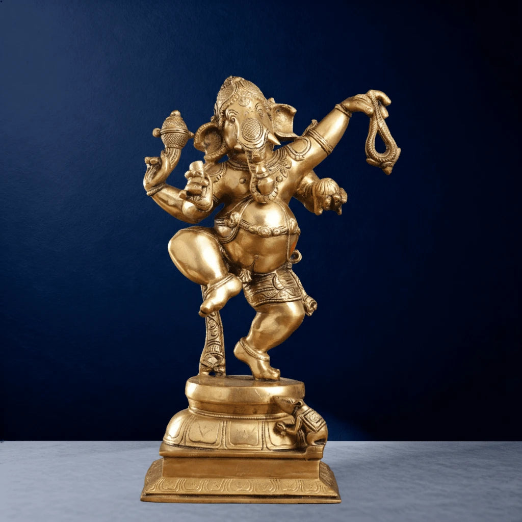 Straight-on zoomed shot of gold-finish dancing Ganesha statue with vahana mouse on base