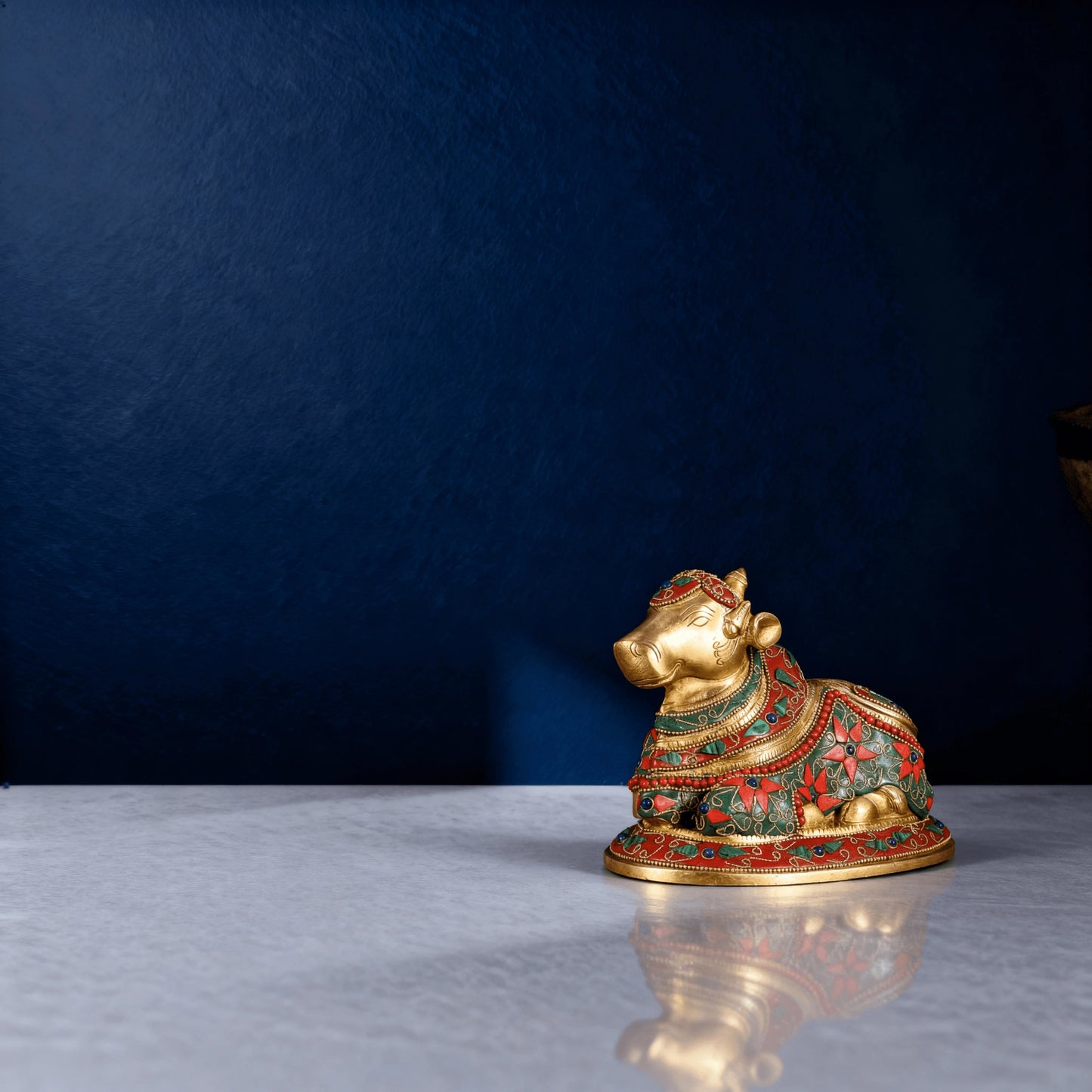 small brass nandi statue with colourful meenakari detailing placed on a marble surface