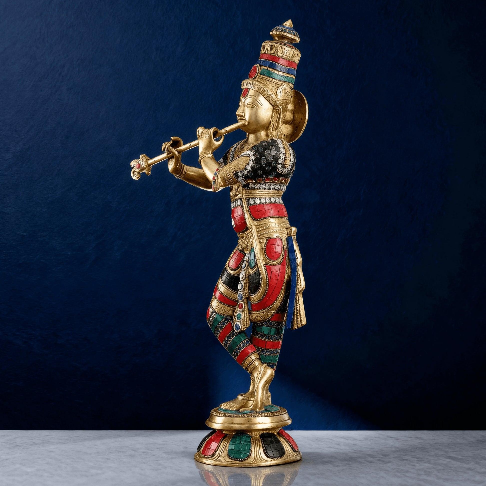 Side-angle view of brass hand-painted Krishna statue with flute