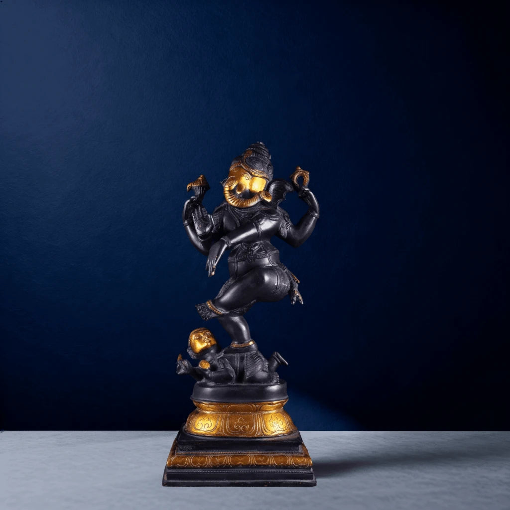 Straight-on shot of black and gold dancing Lord Ganesha sculpture standing on demon figure base