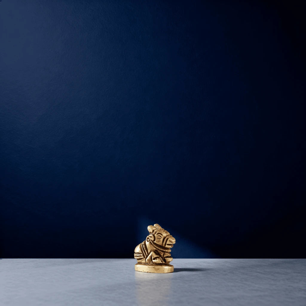 Small brass Nandi miniature idol placed on a light marble surface with a dark blue background