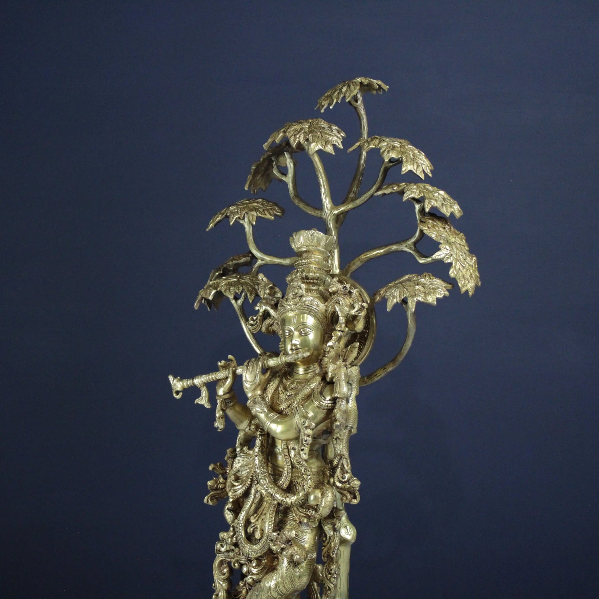 Decorative Krishna statue with intricate designs on a dark blue background