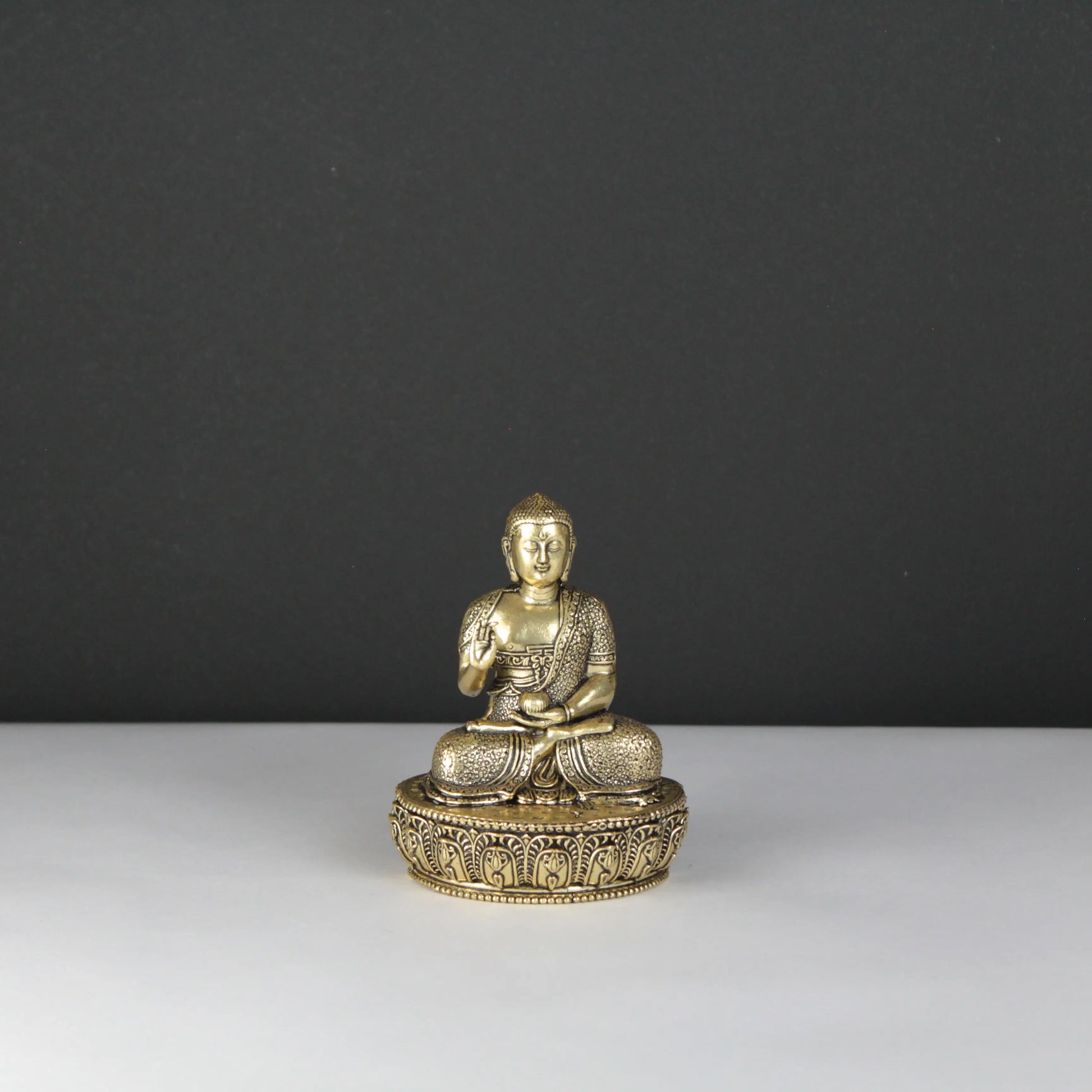 Brass Buddha statue on a dark gray background