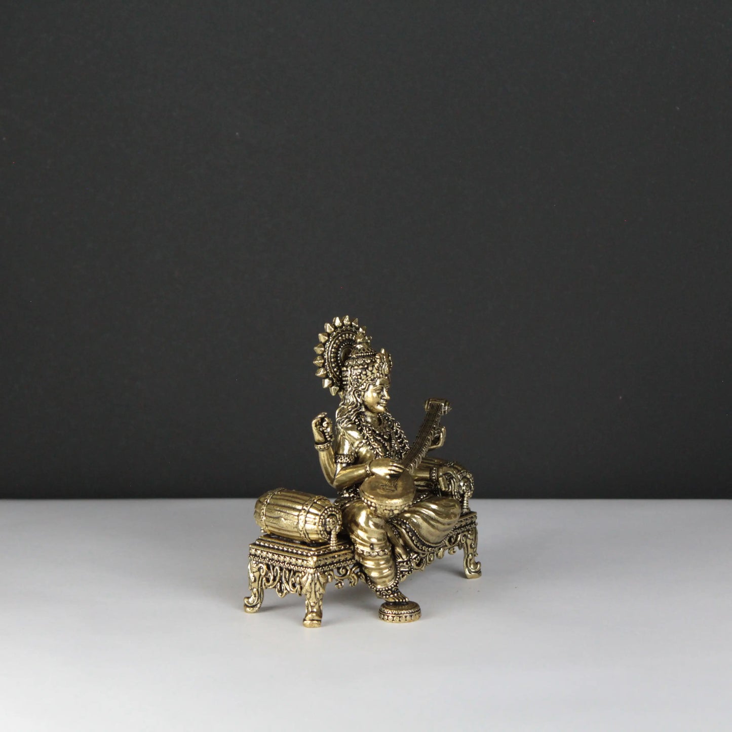 Decorative brass statue of a seated figure on a black and white background