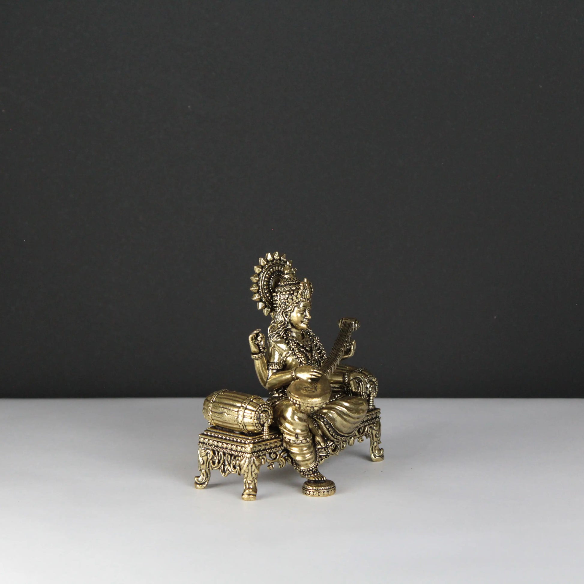 Decorative brass statue of a seated figure on a black and white background