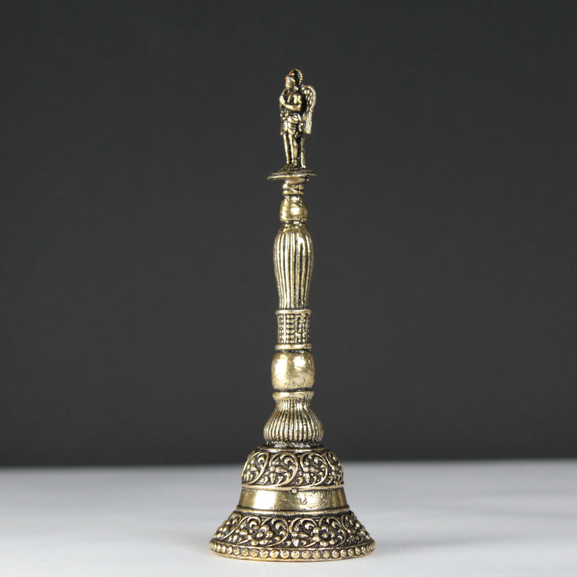 Decorative brass bell with intricate designs on a black background