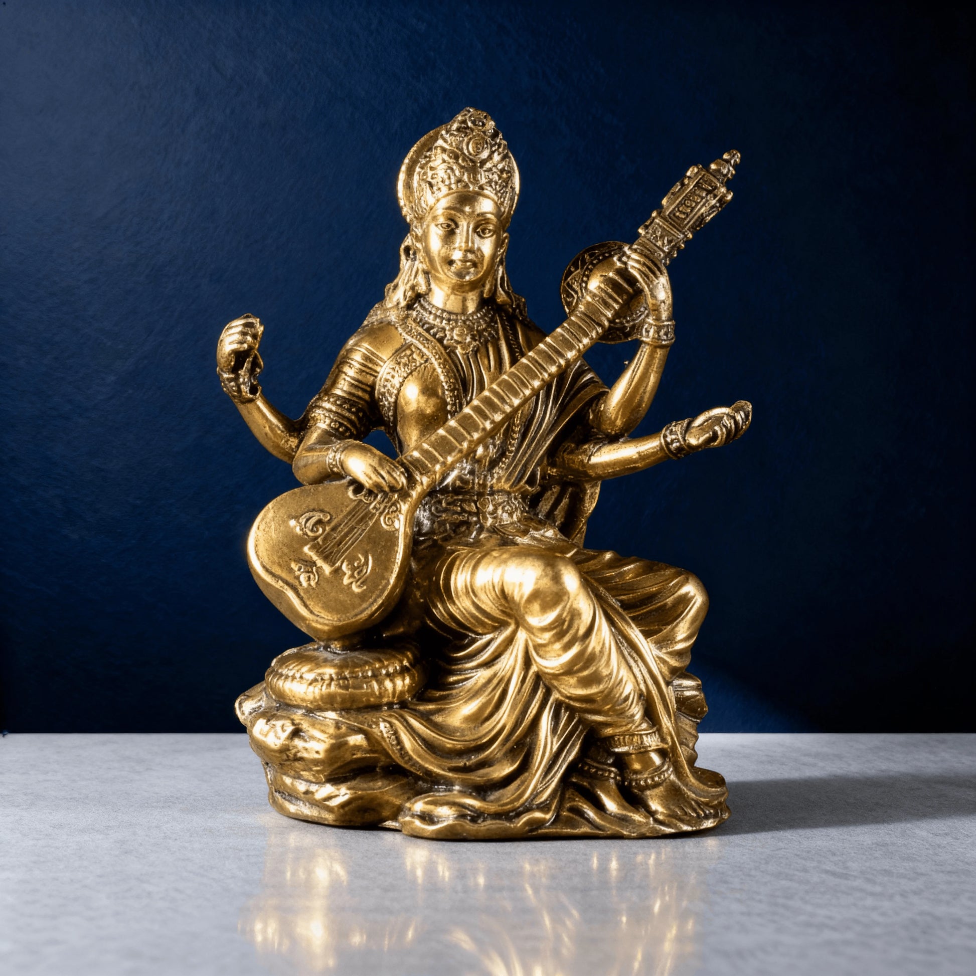 front-facing brass Saraswati statue seated on a sculpted base, showing clean detailing and warm metallic shine in studio lighting