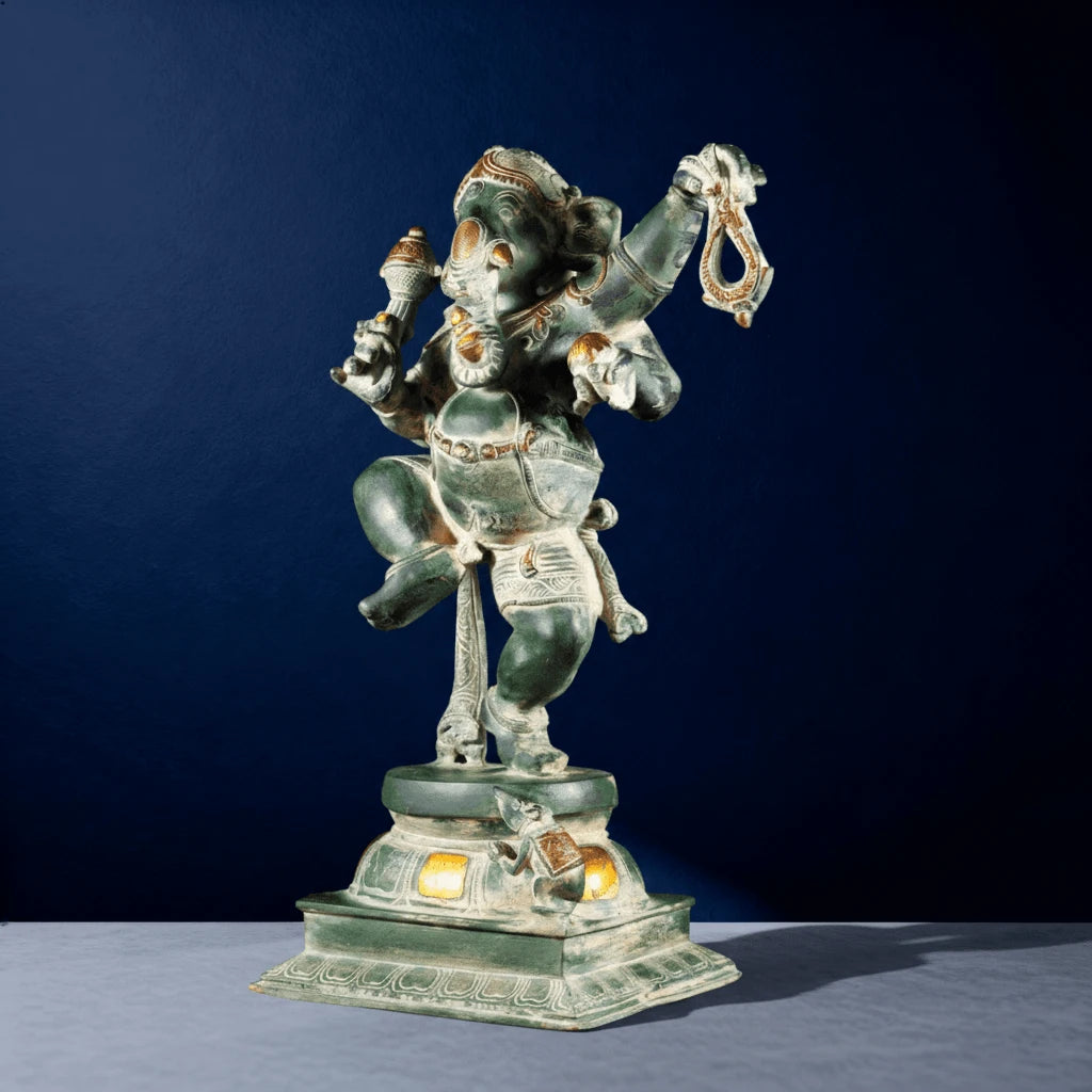 Side view of green oxidized dancing Ganesha statue with yellow-lit base on decorative pedestal