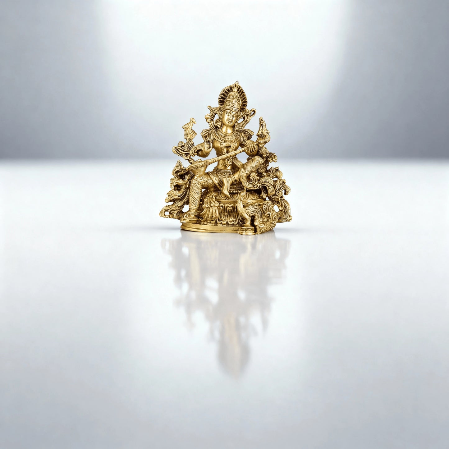 full-length shot of brass Saraswati idol placed on a reflective surface with a clean, minimal background