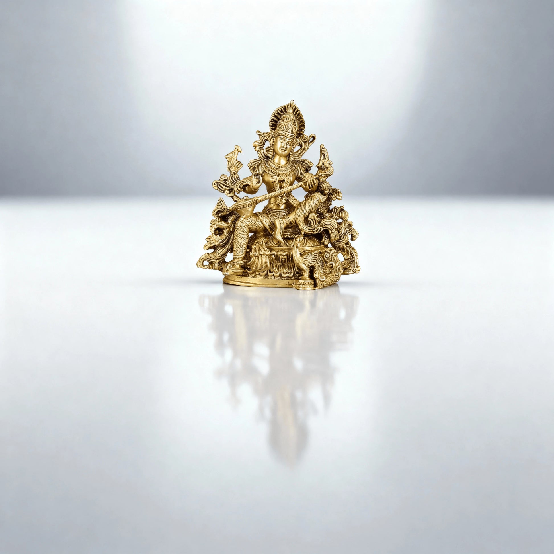 full-length shot of brass Saraswati idol placed on a reflective surface with a clean, minimal background
