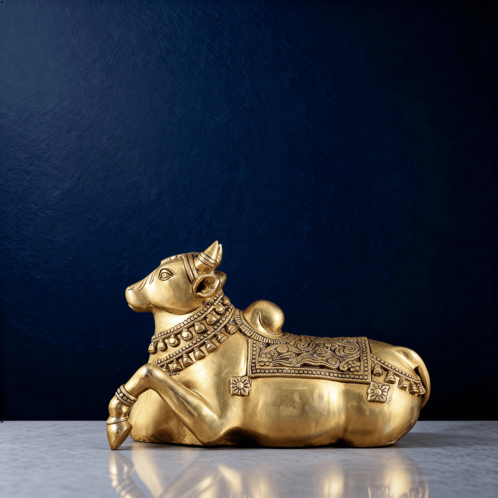 Full side view of brass Nandi statue resting on a smooth marble surface