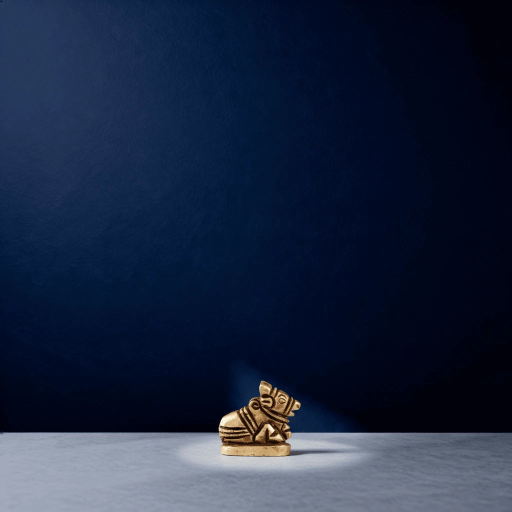 Miniature brass Nandi idol centered on a tabletop with dramatic lighting