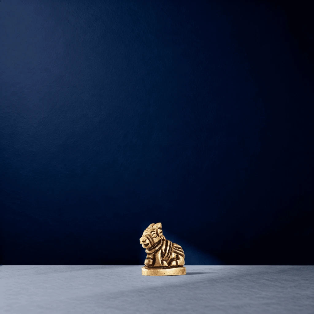 Close-up studio shot of a small brass Nandi figurine on a marble surface