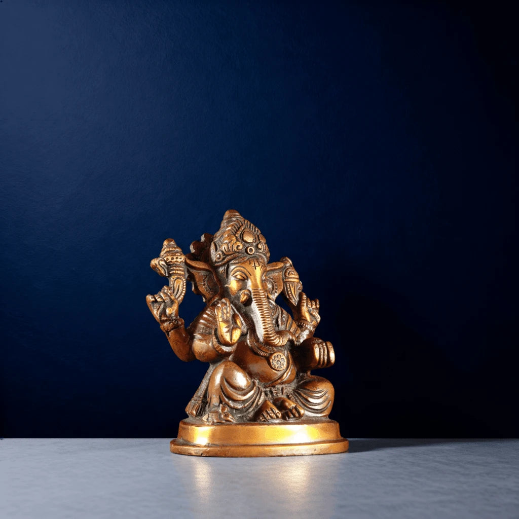 Antique brass Lord Ganesha idol with intricate detailing on a dark blue background