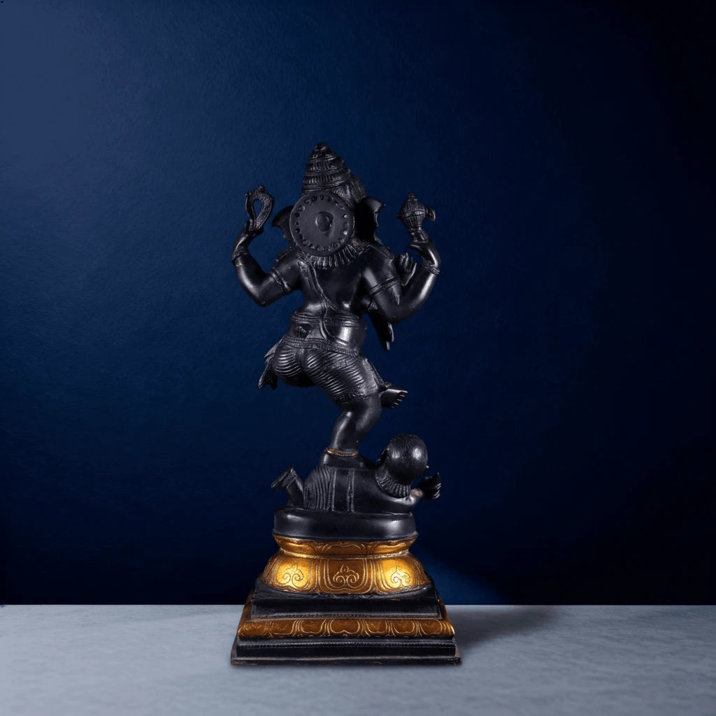 Rear view of matte black Ganapati sculpture with four arms and intricate detailing on golden base